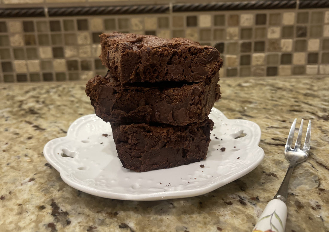 A stack of brownies on a white tea plate next to a fork.